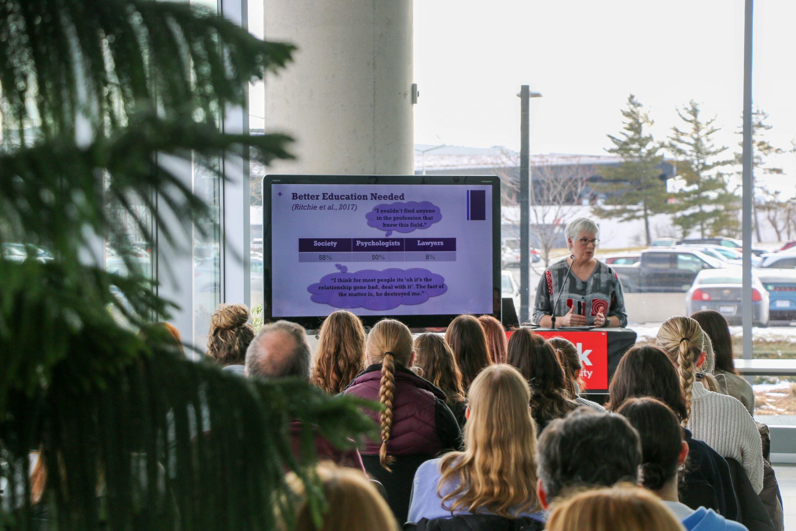A person stands at a lectern and speaks to an audience.