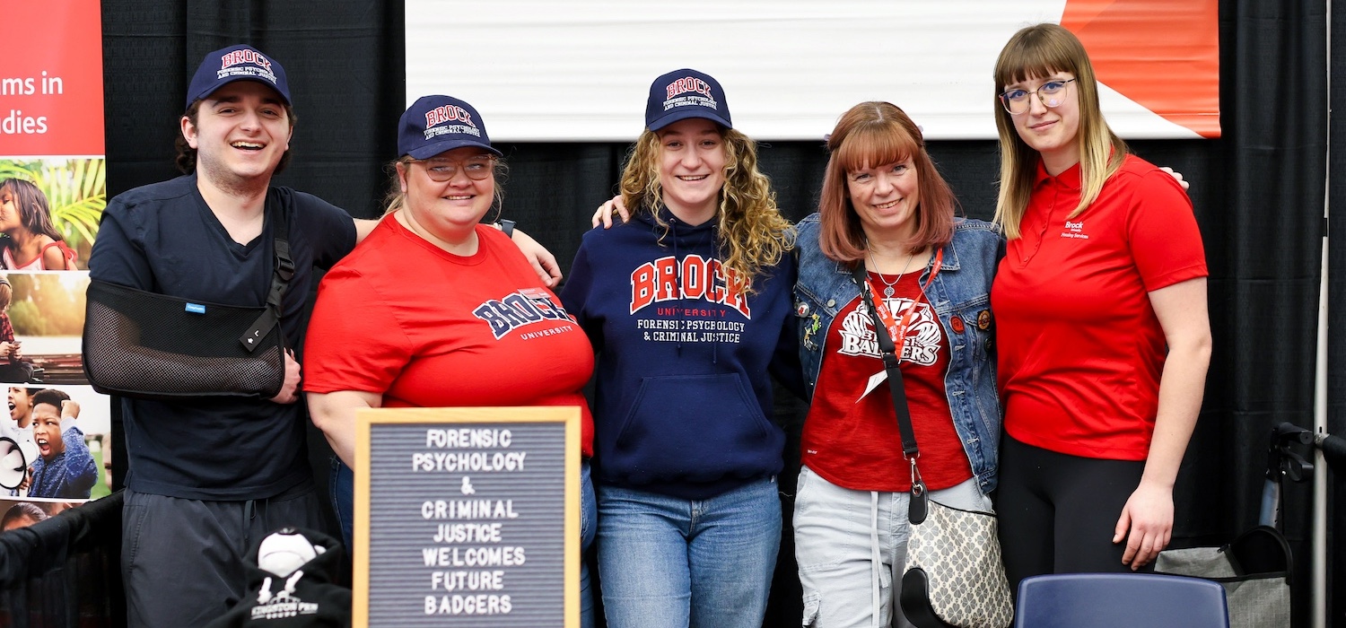 A group of five people in Brock University clothes posing for a group photo.