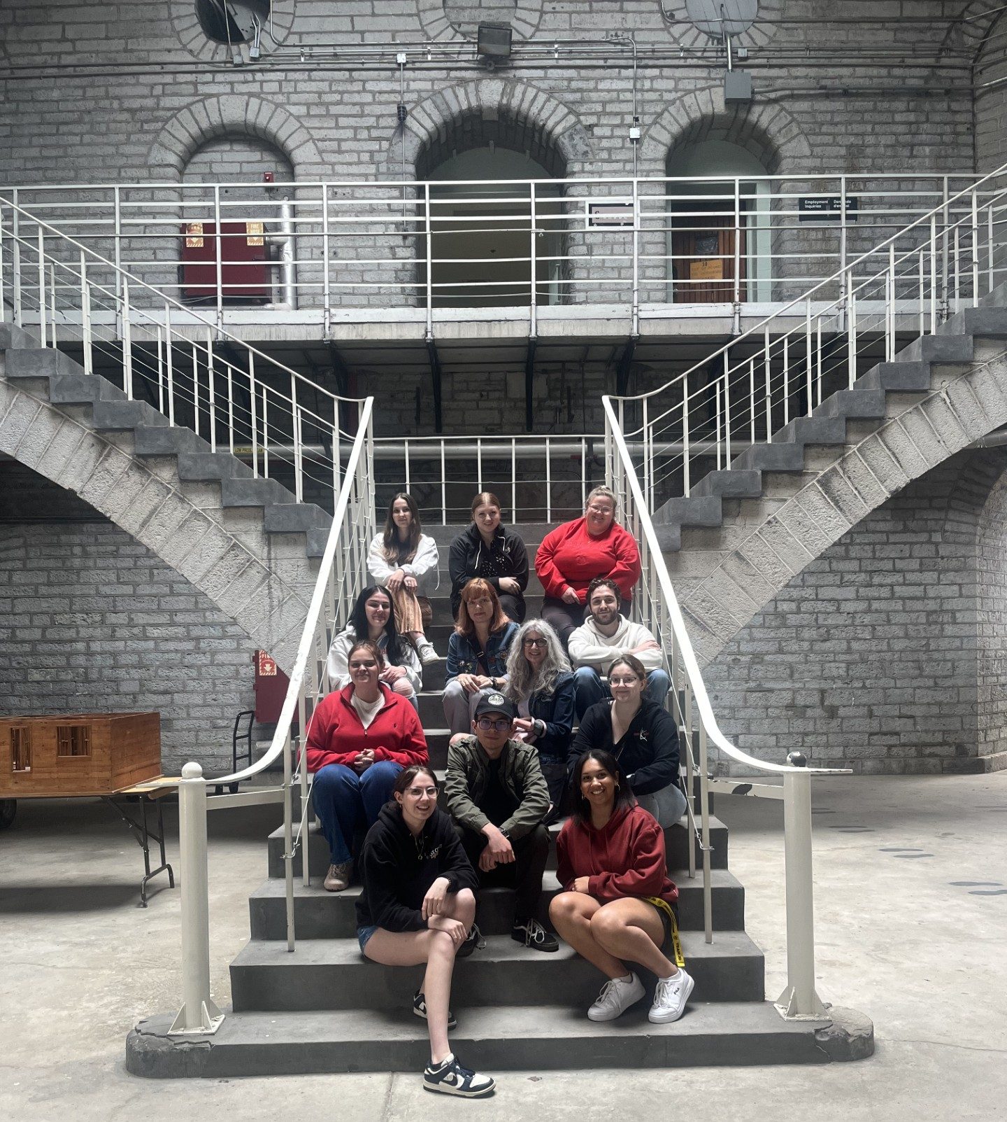 A group of twelve people sitting on a staircase inside a prison.