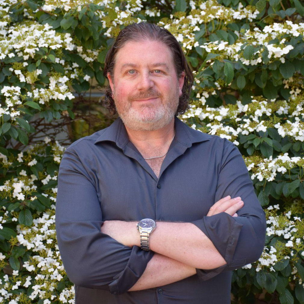 Gordon Hodson in front of a flowering tree on Brock’s main campus.