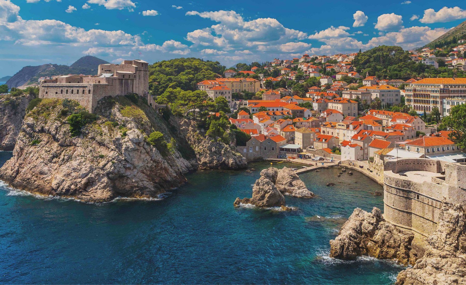 White buildings with orange roofs on a hilly coastline in Croatia. Castles on cliff edges 