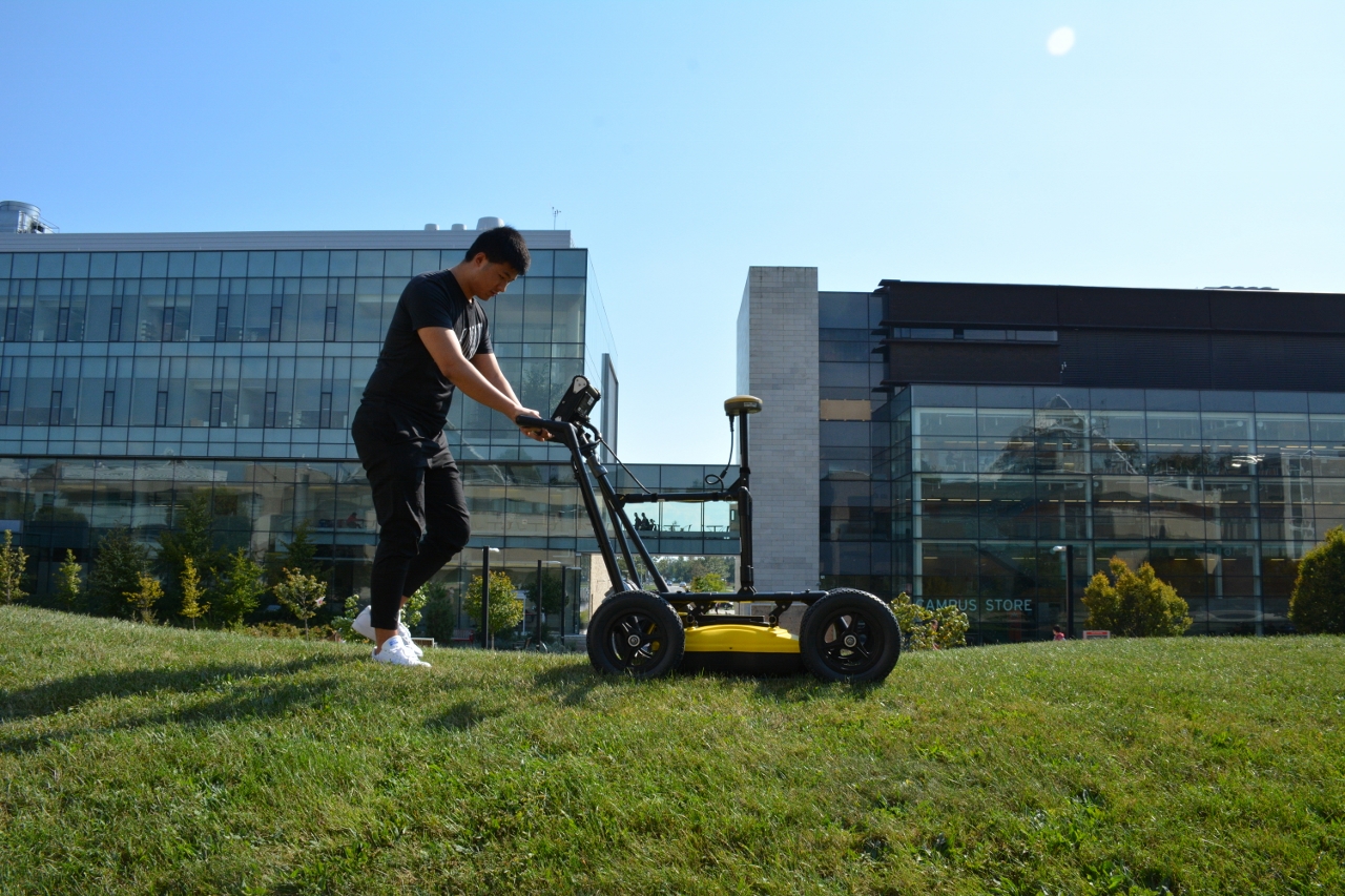 Student using Ground Penetrating Radar technology in GEOG 3P56 course outside on a hill