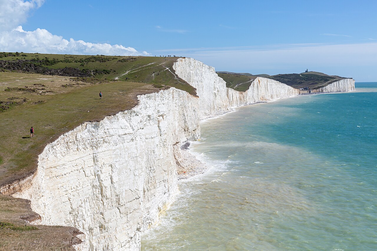 Seven_Sisters-Wikiedia Commons White chalk sea cliffs over a channel of blue water.