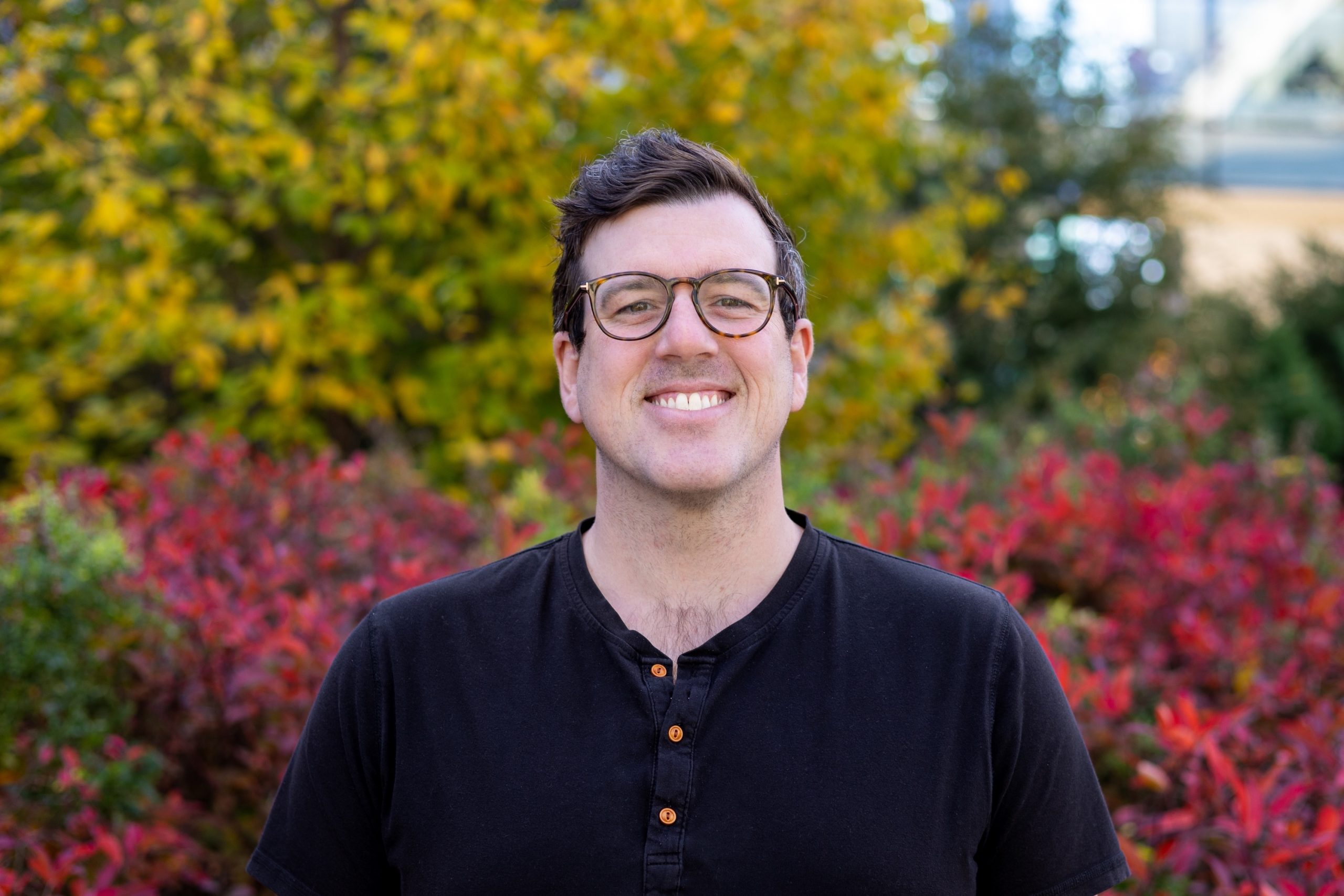 Michael Gordon standing in front of trees with fall-coloured leaves.