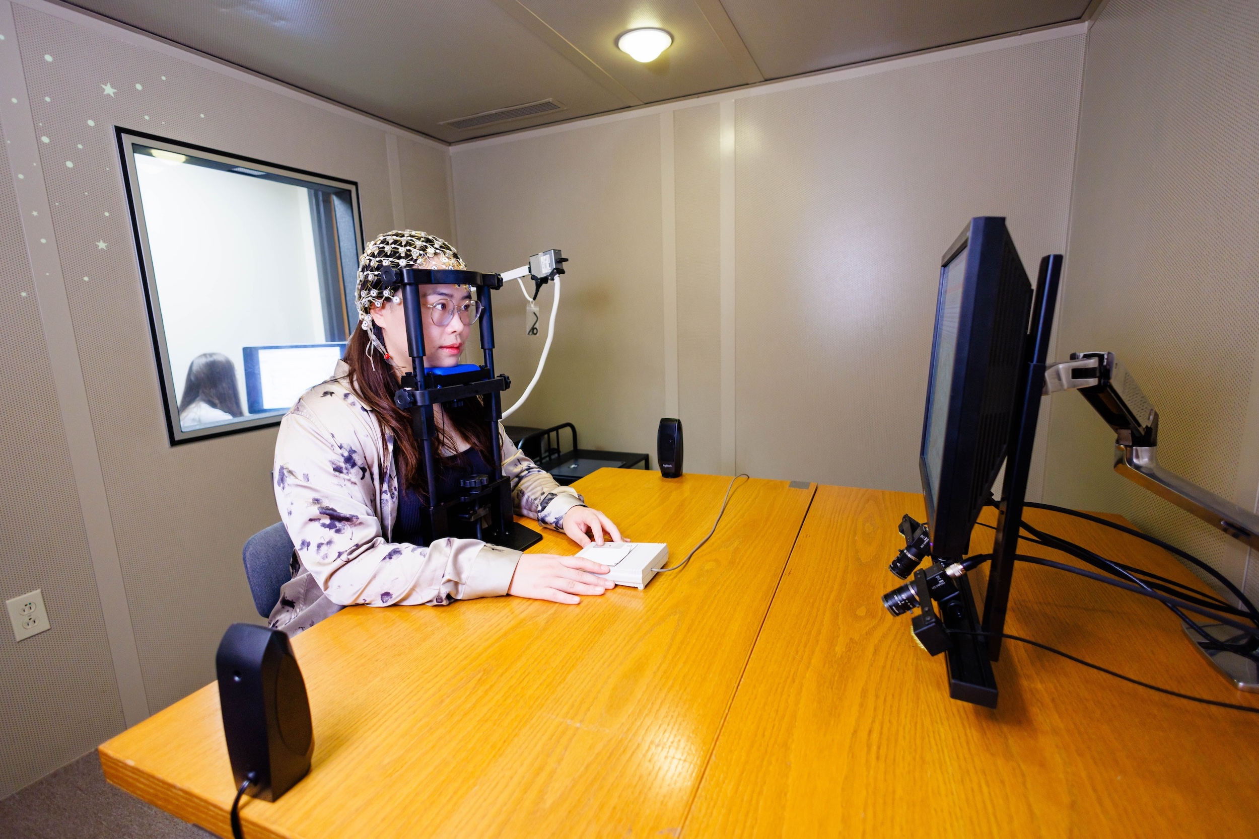 A person wearing an electroencephalogram set-up for a brain activity study while sitting in front of a computer.
