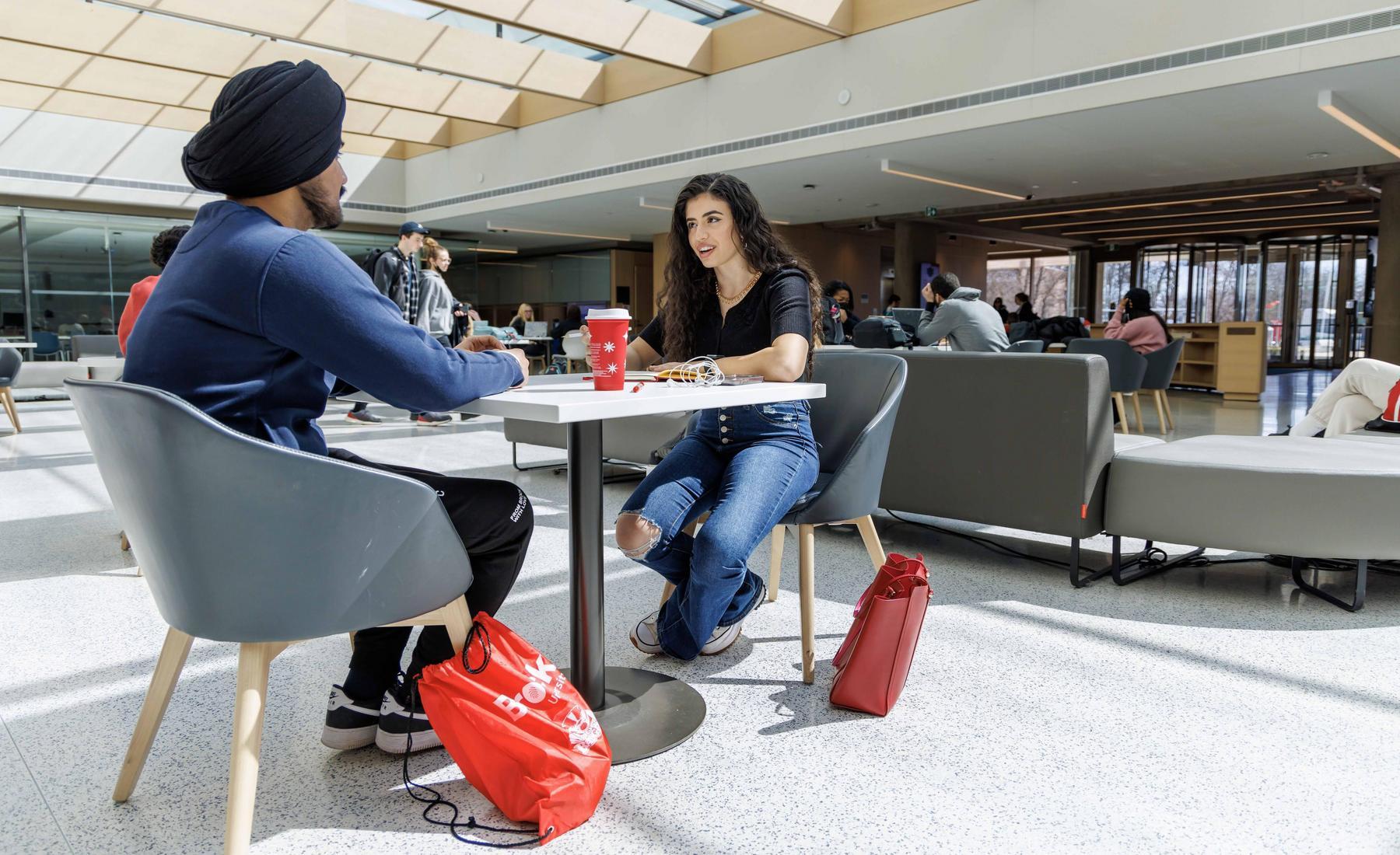 Two students sitting together at a table in Brock University's Rankin Family Pavilion. 