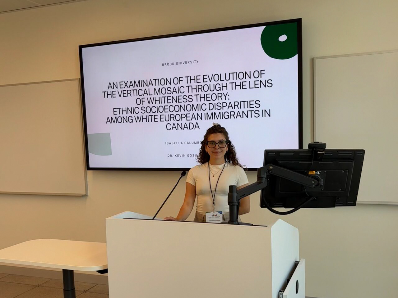 Brock University Social Justice and Equity Studies student Isabella Palumbo standing at a lectern with a presentation projected on a screen in the background.
