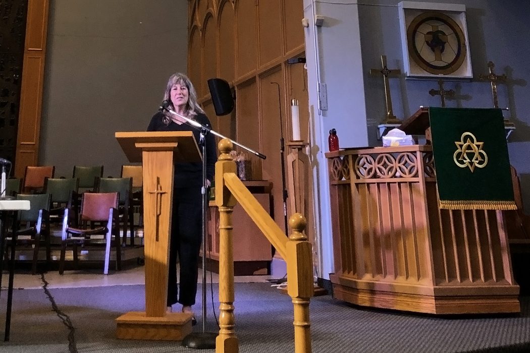 Rev. Karen Orlandi delivering closing remarks in a church.