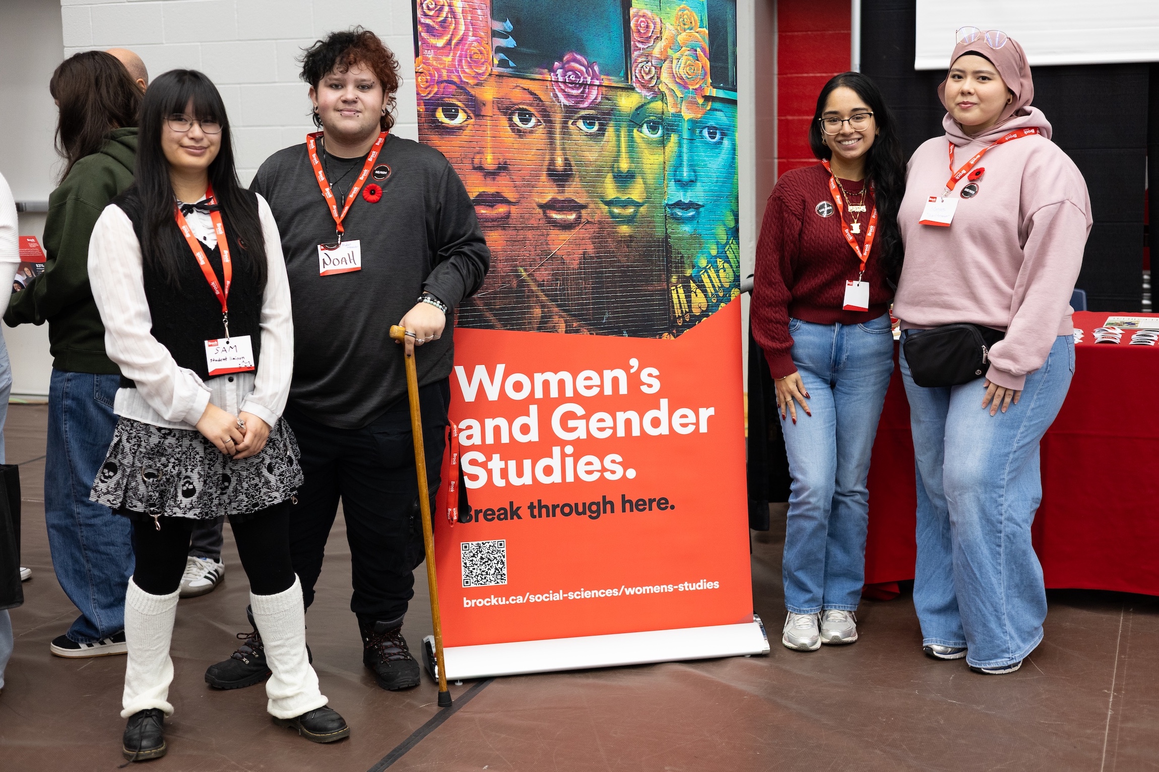 Four people standing around a colourful Women's and Gender Studies pullup banner.