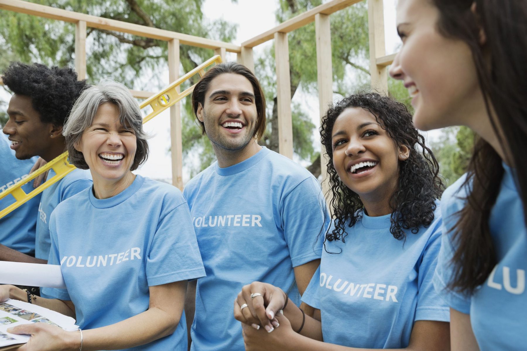 a group of smiling people with volunteer written across their matching t-shirts