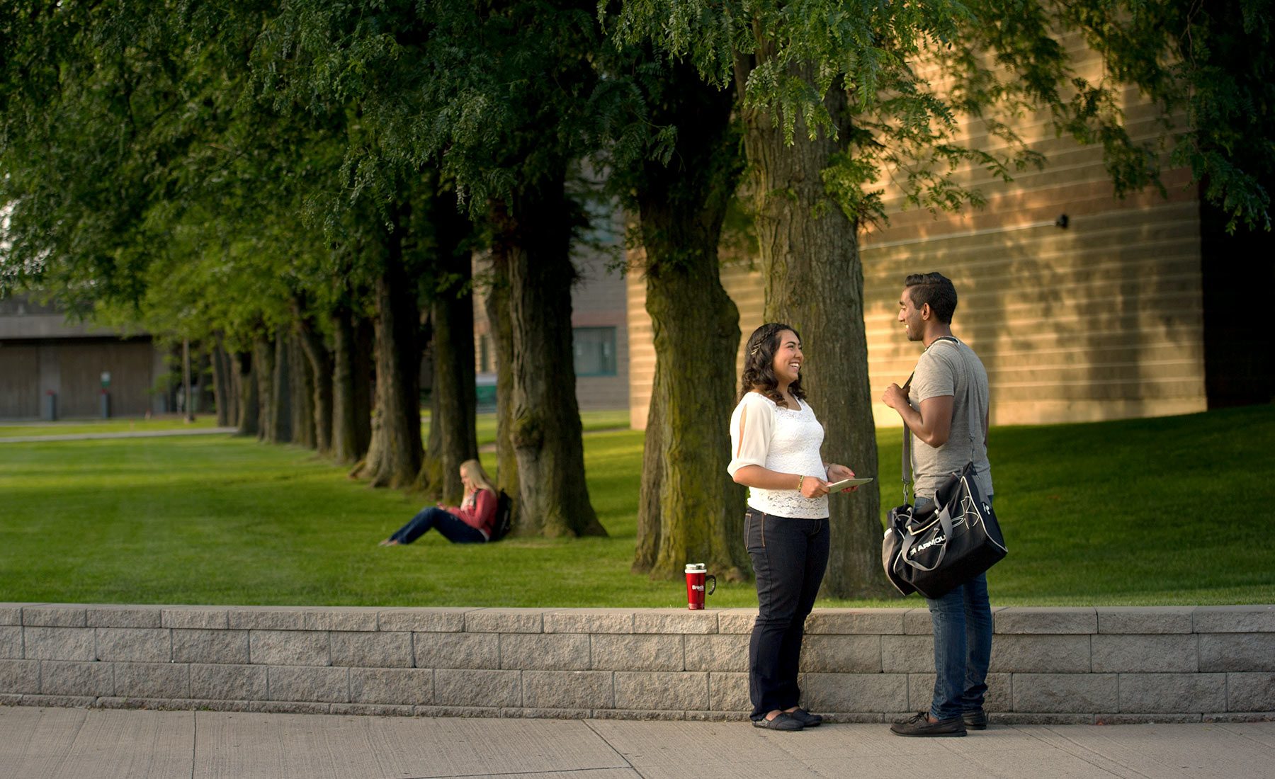 Two students stand outside in front of Schmon Tower talking 