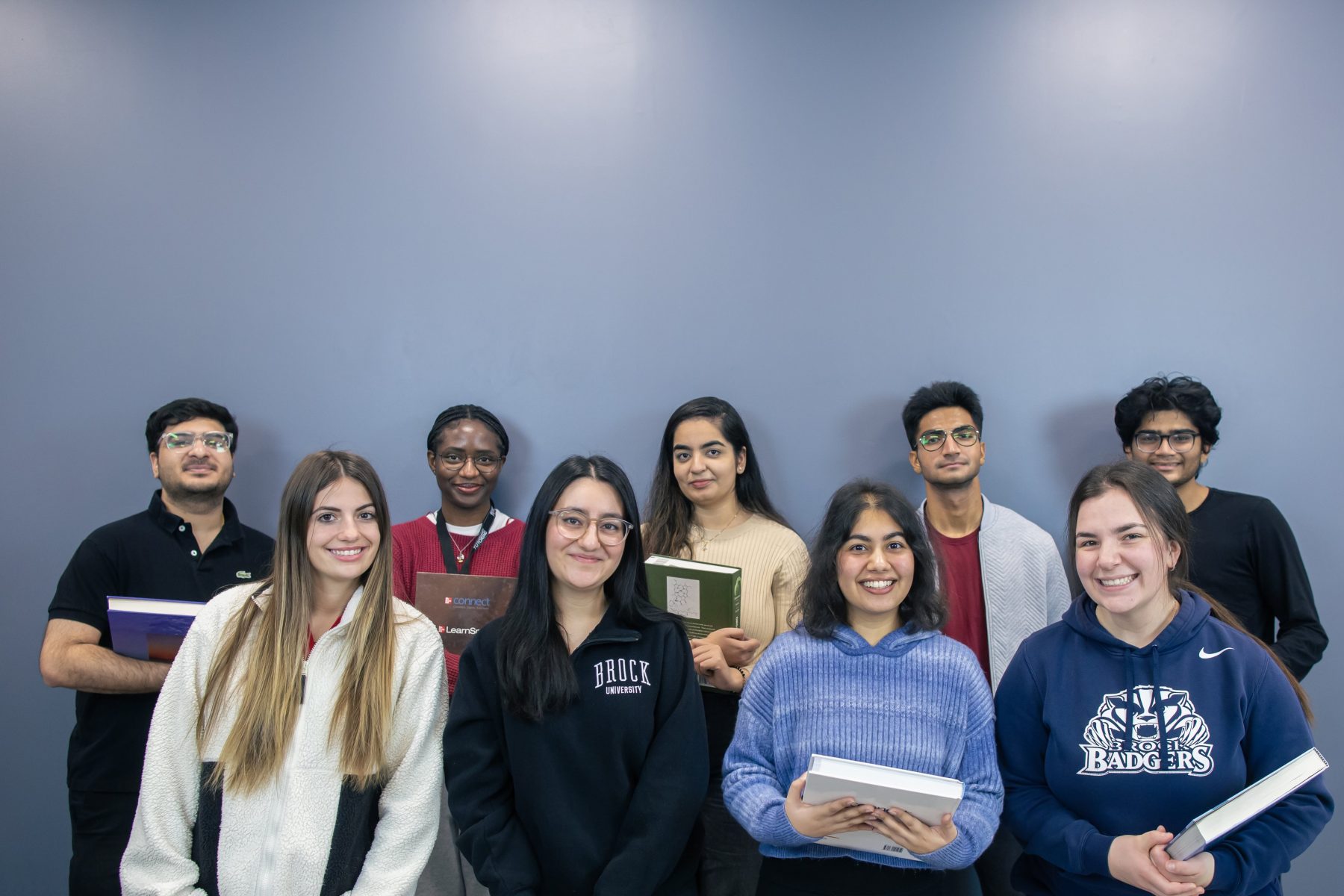 Nine university students holding textbooks smiling