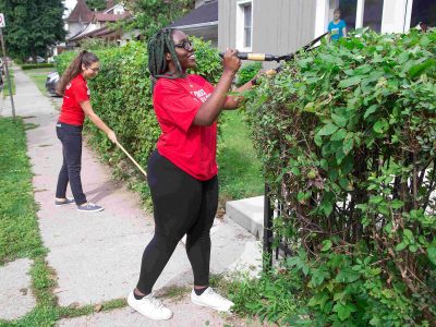 Two students raking and trimming a hedge at a Brock Cares project