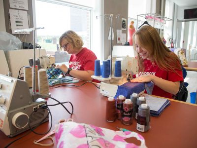 Two students wearing Brock Cares shirts using sewing machines