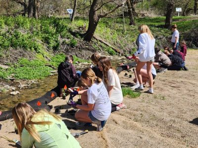 group of young students do research alongside a river
