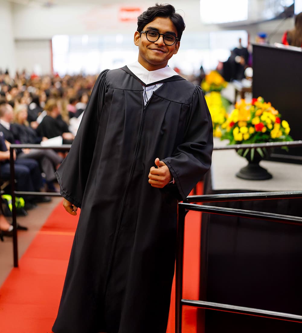 Brock graduate in gown giving a thumbs up as he received his degree. 