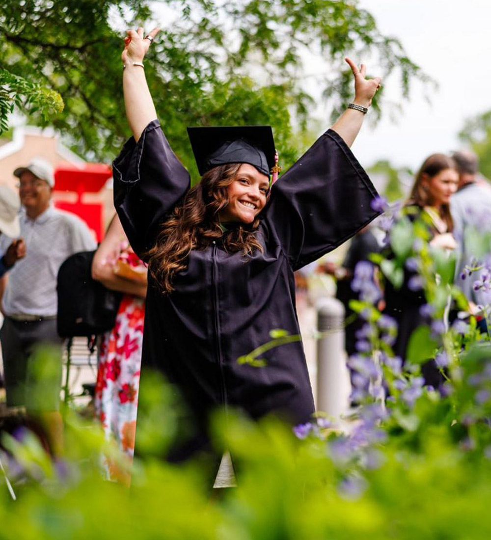 Brock graduate in gown celebrating following a Convocation ceremony. 