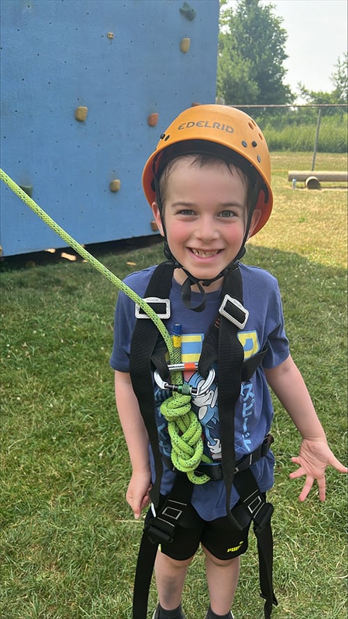 Child in climbing gear in front of ropes course