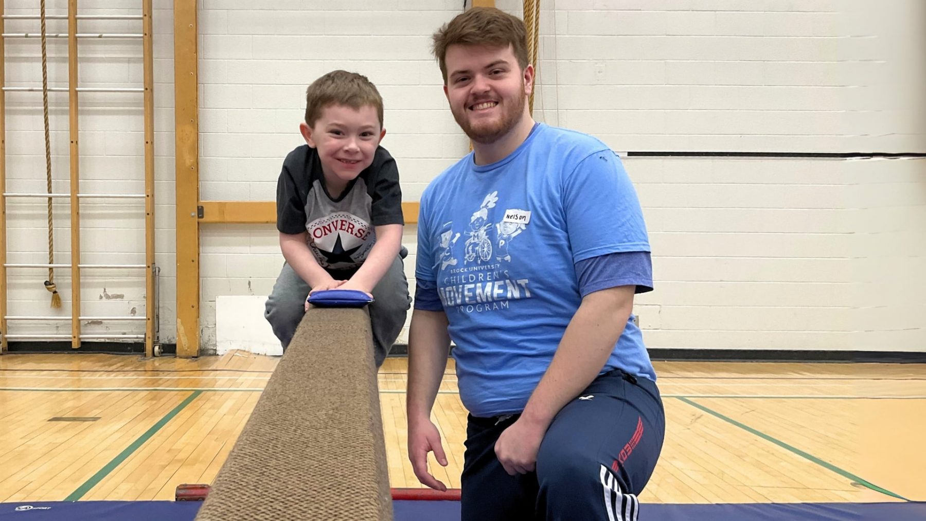 Child on Balance beam laughing while councillor smiles