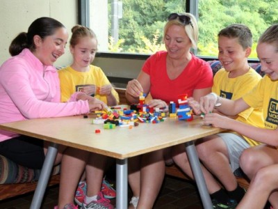 Campers and instructor sitting at a table playing Lego