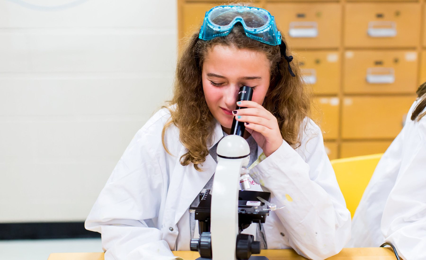 young student looking through microscope 